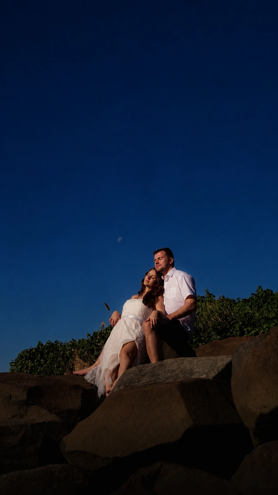 Casal abraçado em uma paisagem de pedras sob o céu azul