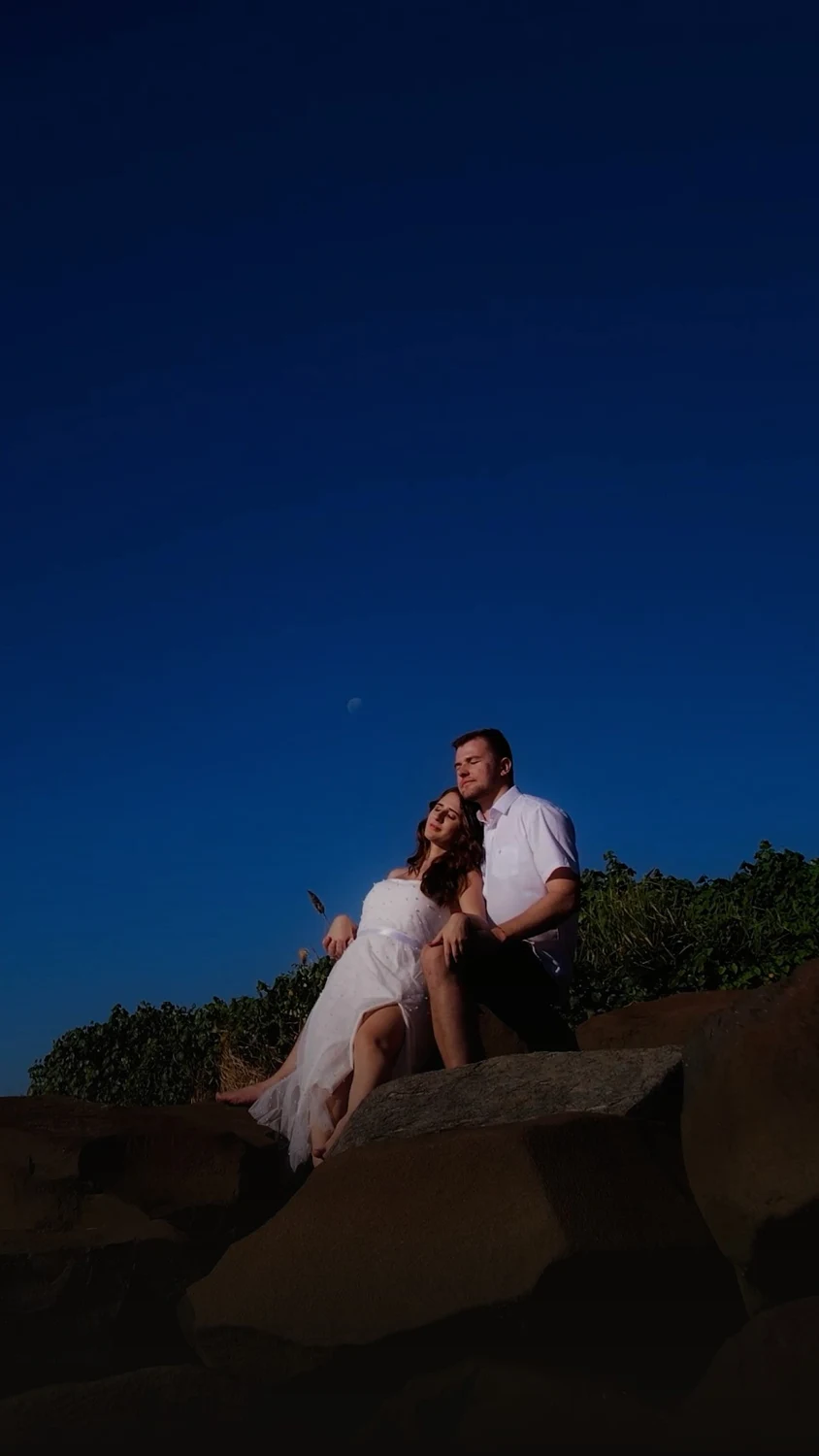 Casal abraçado em uma paisagem de pedras sob o céu azul